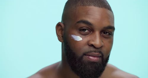 Cream, smile and skincare with face of black man in studio for cosmetics, dermatology or self care