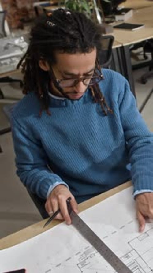 Architect at Desk Drawing Blueprints in Office