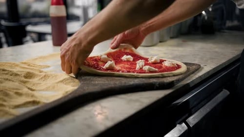 Professioneller Koch macht traditionelle Margarita-Pizza, fügt Tomatenpaste und Käse auf Pizza hinzu
