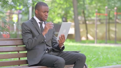 Man in Suit Using Tablet on Park Bench