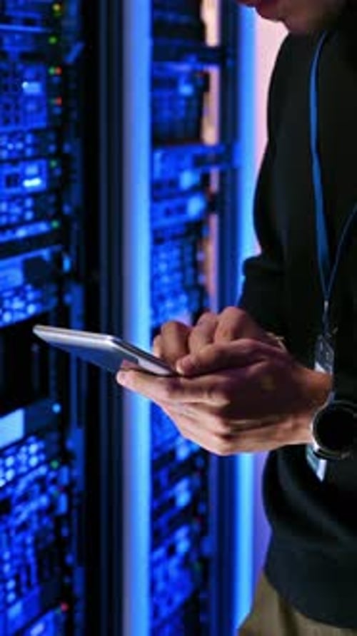 Young Adult Uses Tablet in Server Room