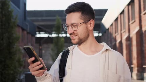 Smiling Man Using Phone in Urban Setting