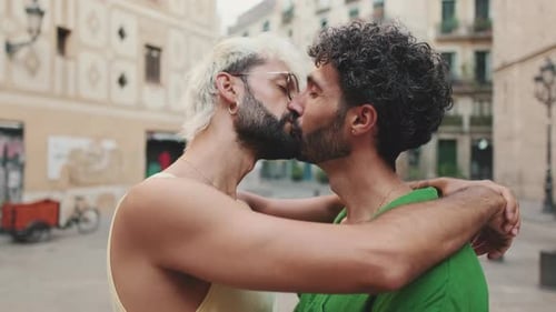 Homosexual couple stands hugging and kissing on street of old city
