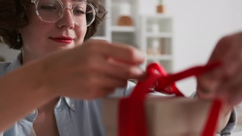 Woman Untying Red Ribbon from Birthday Gift