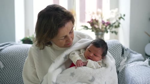 Loving Woman Holding Newborn Baby in Cozy Blanket
