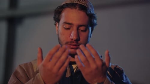 Young Man Praying Quietly With Hands Raised