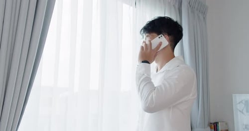 Young Adult Talking on Phone Indoors by Window