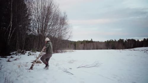 The Man is Transporting a Log for Use as Firewood in the Winter - Static Shot