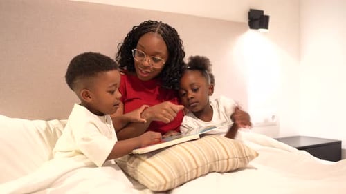 Mother Reading Story to Children in Bed