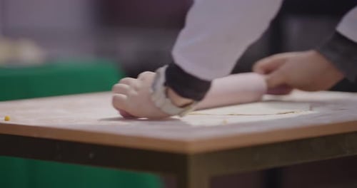 Hände kneten Teig auf einem Holztisch in einer rustikalen Küche