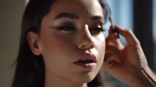 Woman getting eyebrow makeup applied in bright daylight