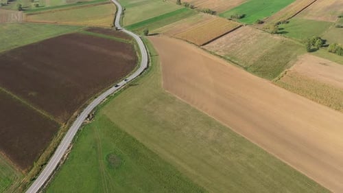 Aerial drone View Over Country Road and Agriculture Fields After Harvest