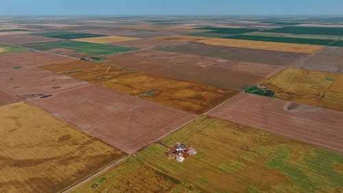 Großes Feld, aufgeteilt in rechteckige Teile. Ein kleiner Standort für die Ölförderung in einem der Gebiete.
