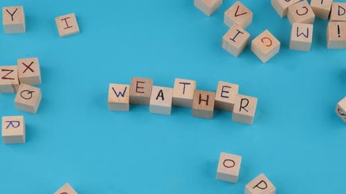 Wooden Blocks Spelling the Word "Weather" on Blue
