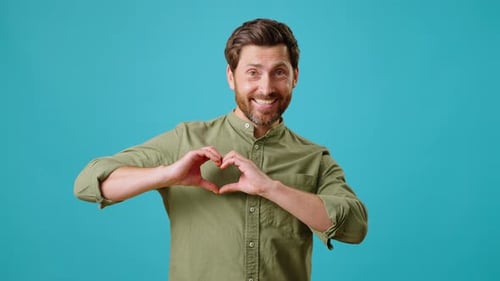 Man Makes Heart with Hands Against Blue Background