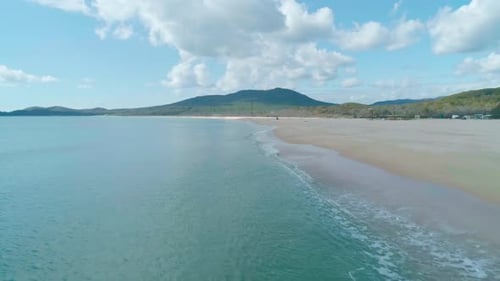 Aerial View of Sandy Beach and Turquoise Ocean Ocean Waves Reaching Shore on a Cloudy Day Camera