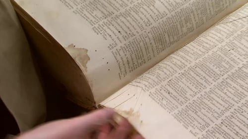 Person Turning the Pages of an Antique Book