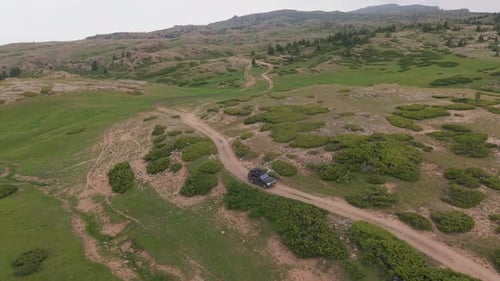Black Suv Driving on Dirt Road in Mountain Meadow