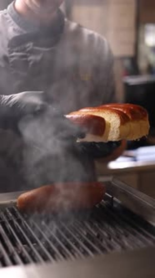 A chef prepares delicious hot dogs in a restaurant.