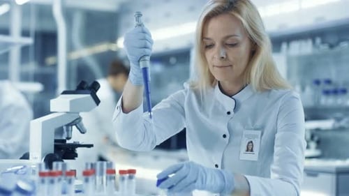 Wissenschaftlerin verwendet Reagenzgläser zum Füllen von Mikropipetten. Wissenschaftler arbeiten in einem großen Labor/