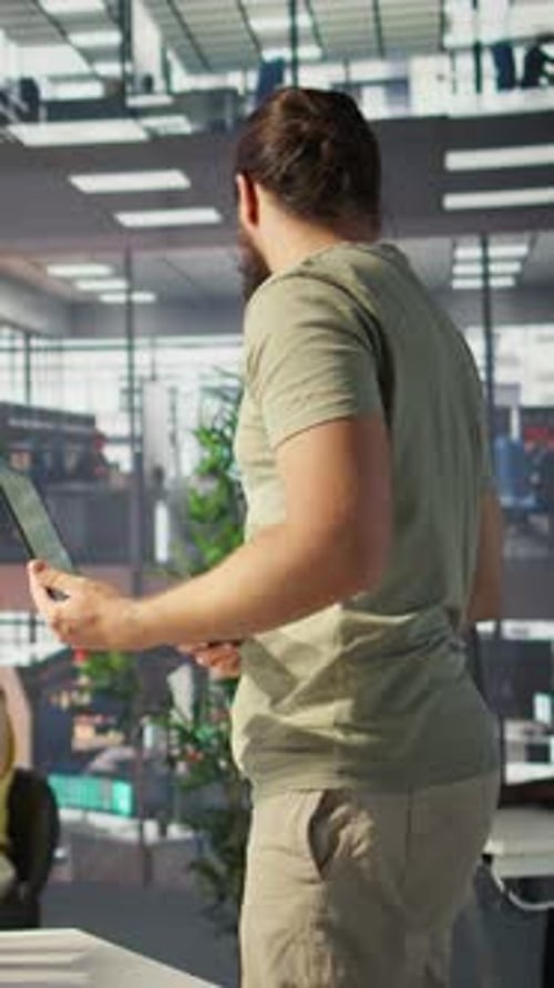 Man Working on Laptop Discusses with Coworker