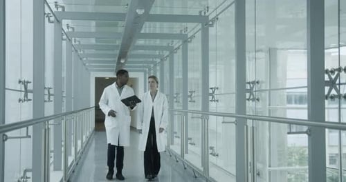 Doctors walking through hospital corridor discussing results on a digital tablet