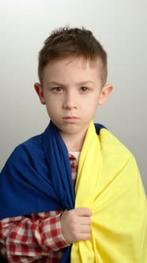 Portrait d'un enfant enveloppé dans un drapeau ukrainien bleu et jaune