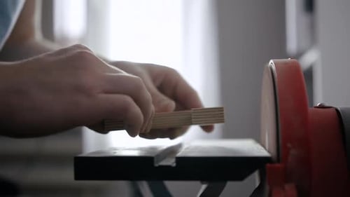 Hands Smoothing Wood Piece Using a Belt Sander