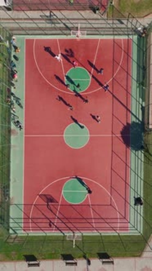 Vertical Video of an Outdoor Basketball Court With Intense Gameplay and Energetic Players Captured
