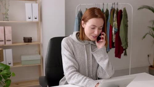 Young Businesswoman Talking on Mobile Phone and Taking Order at Showroom Office