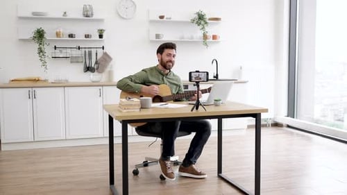 Man Playing Guitar and Live Streaming From Home