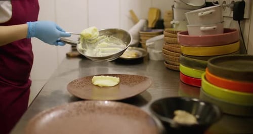 Chef plating mashed potatoes in restaurant kitchen