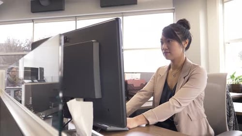 Young chinese businesswoman typing on computer in modern office