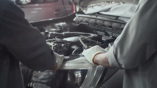 Specialists Searching for Breakdown in Hood of Automobile at Service Station