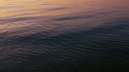 Rosafarbenes Sonnenaufgangslicht, das sich morgens auf der ruhigen Meereswasseroberfläche widerspiegelt