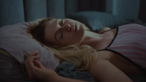Young Woman Sleeping Peacefully in a Dark Bedroom