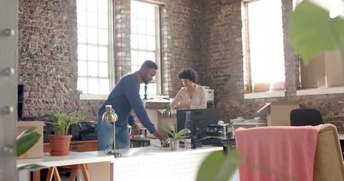 Diverse colleagues unpacking boxes with documents and office items in creative office in slow motion