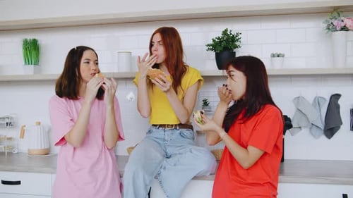 One Girl Sits on the Countertop While Two Others Stand Beside Her They Chat Laugh and Enjoy Their