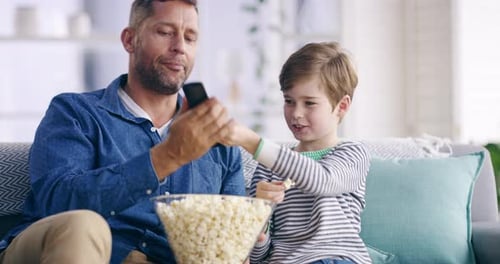 Father and Son Enjoying Popcorn and Television