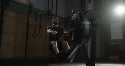 Man Working Out on Rowing Machine in Gym