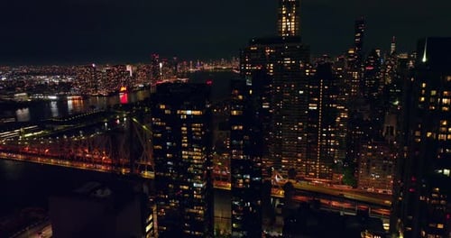 Light in the windows of the buildings in New York. Bridge over the dark river and metropolis skyline