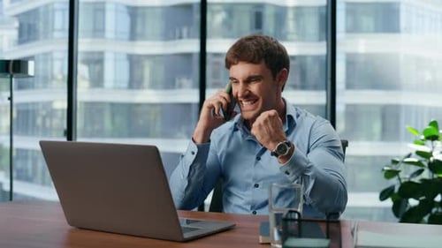 Excited Man Celebrates Good News on Phone at Desk