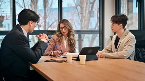 Business meeting in an office, female team leader and two young men discussing business affairs usin