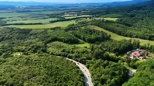 Hills and winding road view. Lush green hills surround a winding road under a bright sky