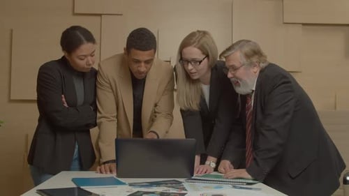 Diverse Team Collaborating on Laptop in Modern Office