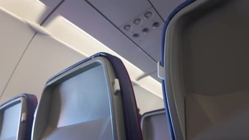 Perspective view between rows of airplane seats, emphasizing the cabin layout and seating design.