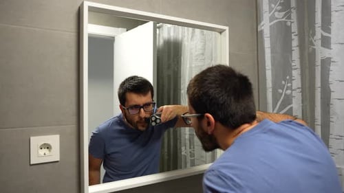 Man Shaving Beard in Bathroom Mirror