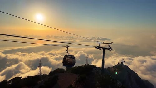Cable Car Ascending Mountain Above Clouds At Sunset