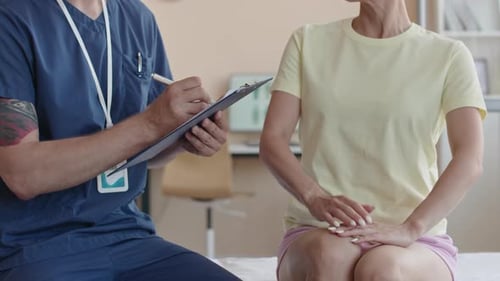 Physiotherapist Taking Notes on Consultation with Female Patient