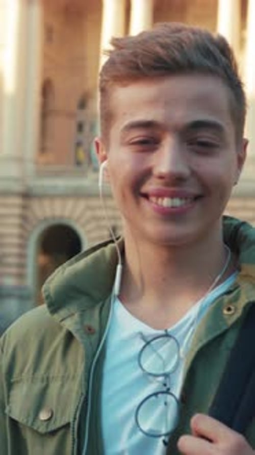 Portrait Young Man with Headphone Backpag Stand Look at Camera Smile Feel Happy on Street Outdoors